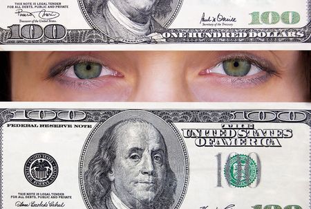 Green female eyes looking through hundred dollars banknote.の写真素材