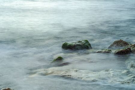 Long exposure sea and green moss stones. Mediterranean sea.の写真素材
