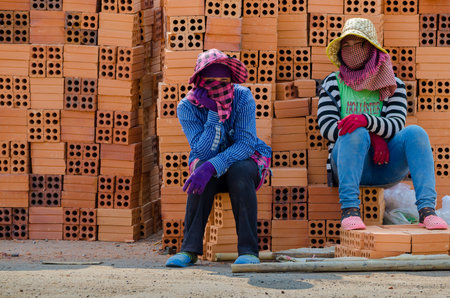 Two women sitting in front of bricks. Cambodia