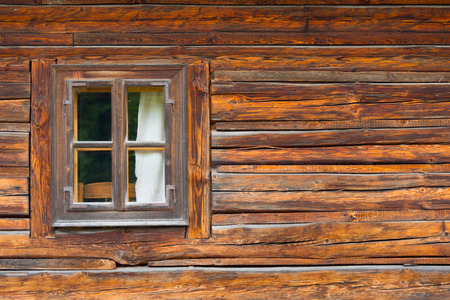 The window of the old wooden log house on the background of wooden wallsの写真素材