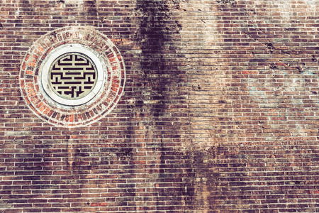 Very old chinese window on brick wall. Hue, Vietnam.の写真素材