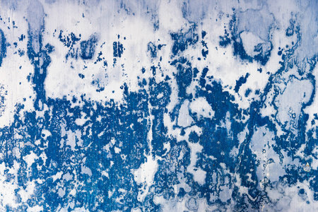 Old white wall with peeling blue color.