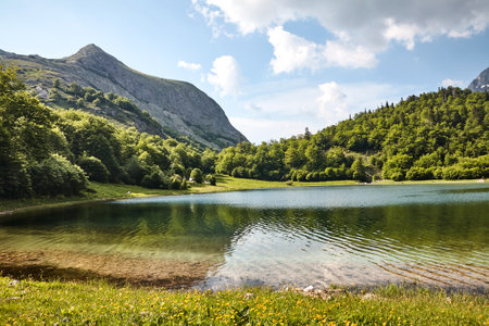 On the lake shore of Lake Herzegovina in Bosnia and Herzegovina in the absolute solitude of the Balkans after a hike on a sunny afternoon with a view of the surrounding mountain peaksの写真素材