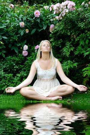Woman meditating in garden with reflection pool in frontの写真素材