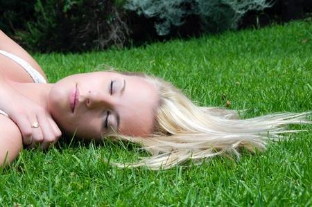 Woman resting on the lawn with her blonde hair spread out in the sunの写真素材
