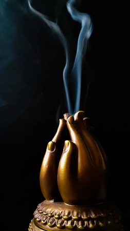 Cone incense burning in a prayer hands burnerの写真素材