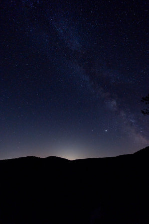 Milky way over the mountains. Night sky with stars and clouds.