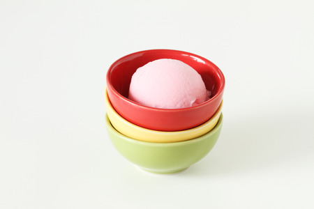 pink ice cream in red ceramic cup on white backgroundの写真素材