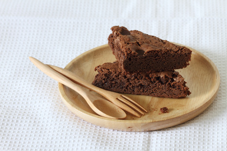 pile of brownie on wooden plate on white fabricの写真素材