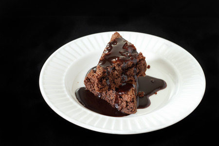 Slices of a brownie on white plate covered with chocolate の写真素材