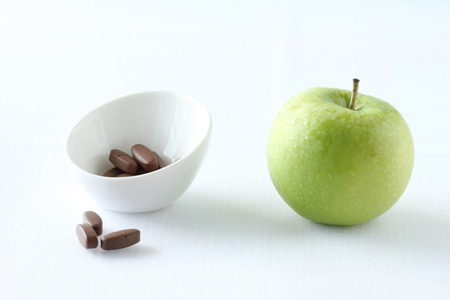 fresh green apple and vitamin pills on white backgroundの写真素材