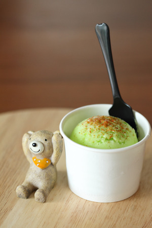 mango ice cream scoop with miniature bear doll on wooden plateの写真素材