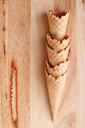 row of empty ice cream cones on wooden backgroundの写真素材