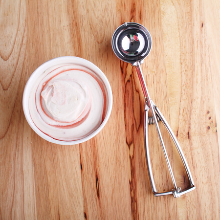 ice cream cup and scooping utensil on wooden backgroundの写真素材