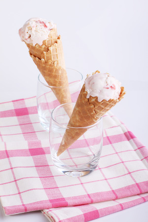 ice cream cones in clear glasses on pink fabric on white backgroundの写真素材