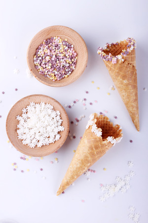 empty ice cream cones with colourful sprinkles on white backgroundの写真素材