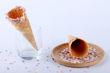 empty ice cream cones with colourful sprinkles on white backgroundの写真素材