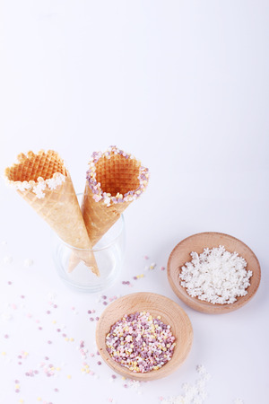 empty ice cream cones with colorful sprinkles on white backgroundの写真素材