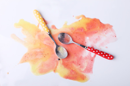 yellow passion fruit and red strawberry ice cream scoops eaten melt on white backgroundの写真素材