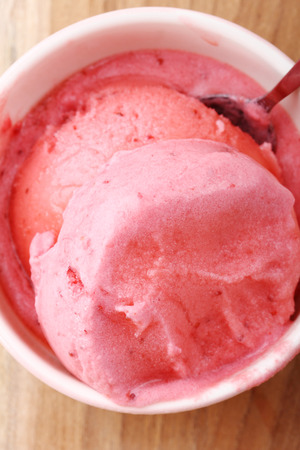 red homemade strawberry ice cream scoop in ceramic cup closeupの写真素材