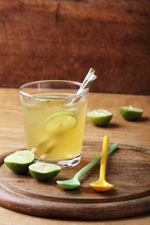 cold gold soft drink from lime and honey with gold straw on wooden boardの写真素材