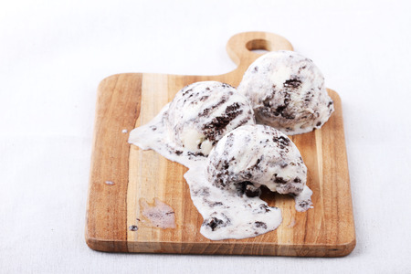 homemade cookie and cream ice cream scoop melting on wooden boardの写真素材