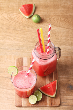 Healthy watermelon lime smoothie and fresh watermelon on a wooden backgroundの写真素材