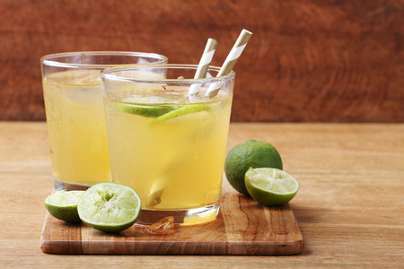 cold gold soft drink from lime and honey with gold straw on wooden boardの写真素材