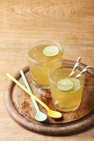 cold gold soft drink from lime and honey with gold straw on wooden boardの写真素材