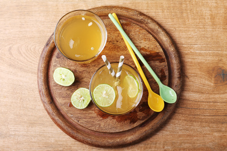 cold gold soft drink from lime and honey with gold straw on wooden boardの写真素材