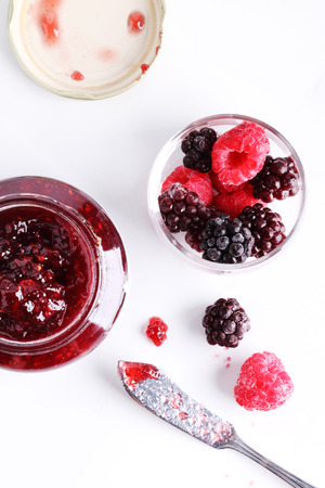 berry jam and raspberry and blackberry on a white marble table.の写真素材