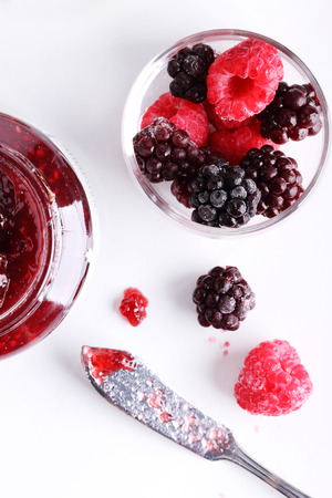 berry jam and raspberry and blackberry on a white marble table.の写真素材