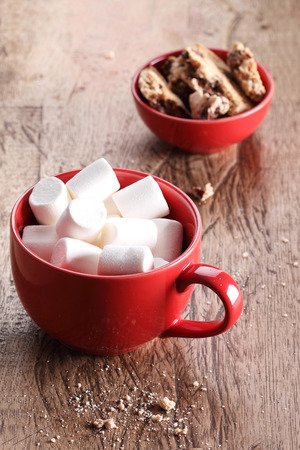 marshmallows and cookies in red cup on wooden tableの写真素材