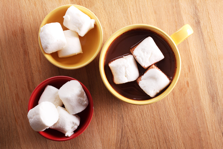 hot chocolate drink and marshmallows in colorful cups  on wooden backgroundの写真素材
