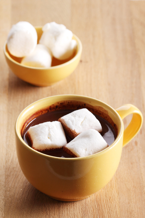hot chocolate drink in yellow cup and marshmallows on wooden backgroundの写真素材
