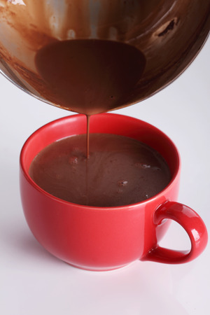 hot chocolate drink pouring into red cup on white backgroundの写真素材