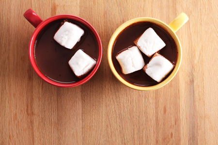 chocolate drink and marshmallows in colorful cups on wooden backgroundの写真素材