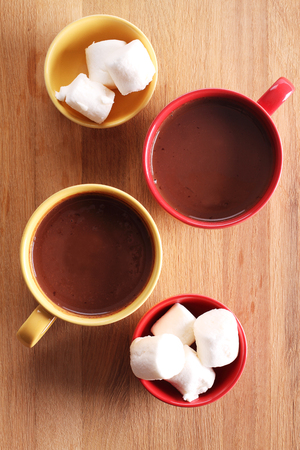 hot chocolate drink in colorful cups and marshmallows on wooden backgroundの写真素材