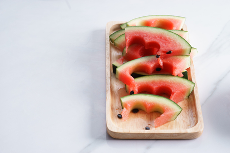pieces of indented watermelon on white marble table with copyspaceの写真素材