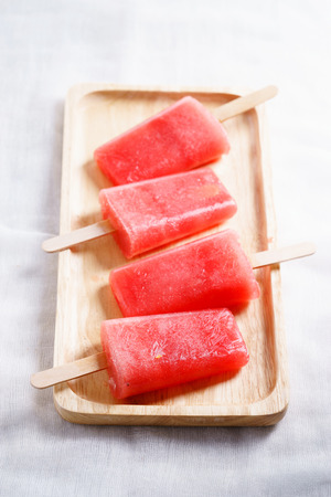 Homemade watermelon popsicles on wooden plate on white backgroundの写真素材