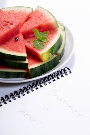 Slices of fresh watermelon with notebook paper on white marble backgroundの写真素材