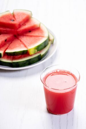 Healthy watermelon drink and fresh sliced watermelon on white wooden backgroundの写真素材