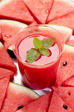 Healthy watermelon drink and fresh sliced watermelon on white wooden backgroundの写真素材