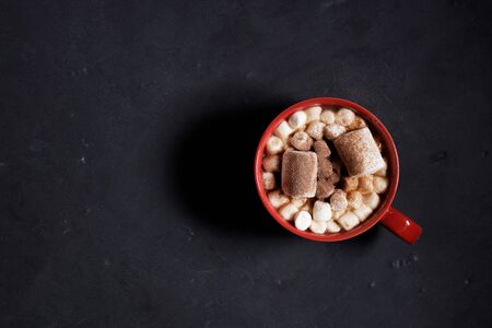 Red ceramic cups of hot cocoa with marshmallows on top of black rustic backgroundの写真素材
