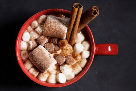 Red ceramic cups of hot cocoa with marshmallows on top of black rustic backgroundの写真素材