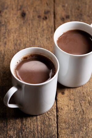 White ceramic cups of hot cocoa on top of rustic wooden backgroundの写真素材