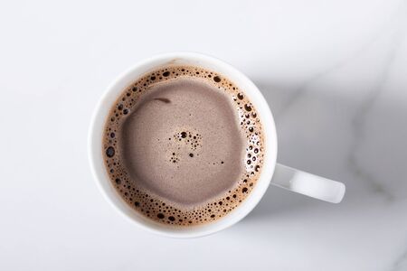 White ceramic cup of hot cocoa on top of white marble background, top viewの写真素材