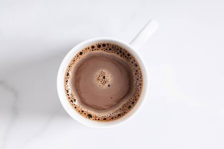 White ceramic cup of hot cocoa on top of white marble background, top viewの写真素材