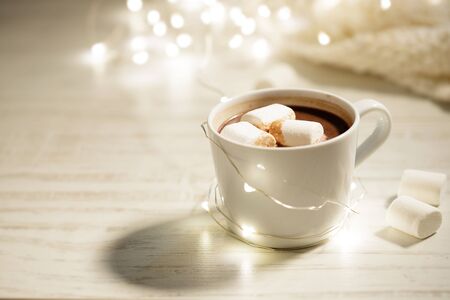 White ceramic cup of hot cocoa with marshmallows on white wooden backgroundの写真素材