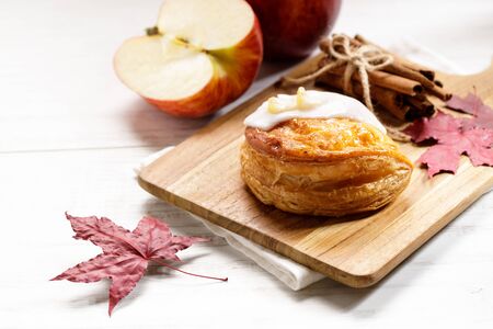 piece of cinnamon apple pie on a wooden board with fresh apple in background, autumn food conceptの写真素材